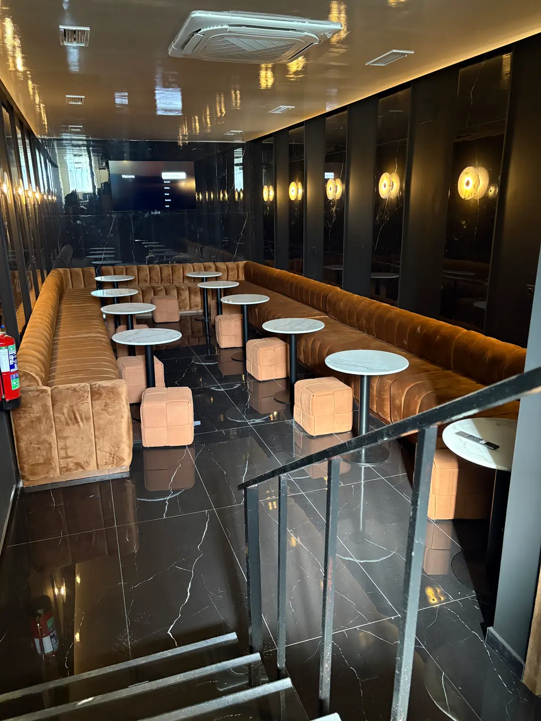 El salón: bancos corridos tapizados, mesas de mármol y apliques de luz cálida